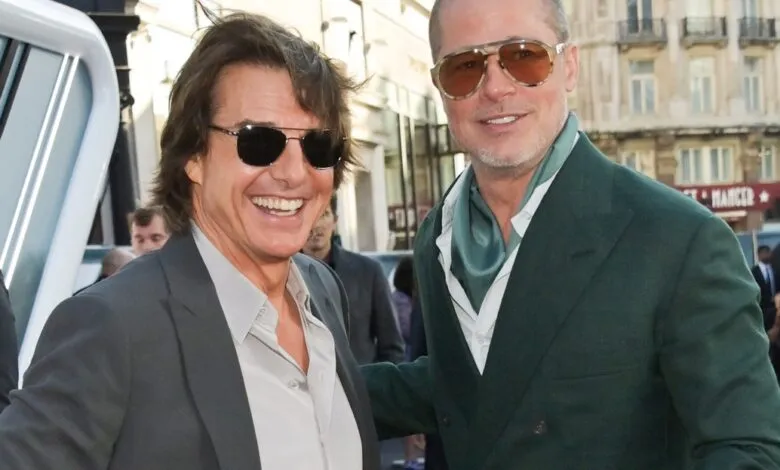 Tom Cruise and Brad Pitt smiling together on a red carpet.