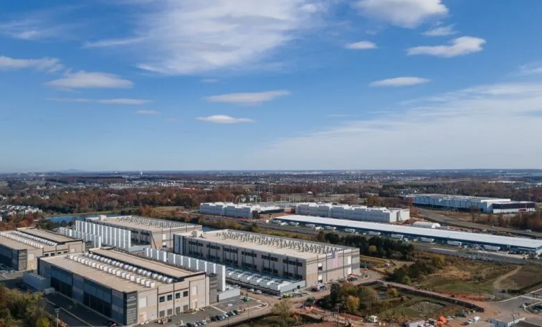 Aerial view of large data centers surrounded by autumn trees under a blue sky.