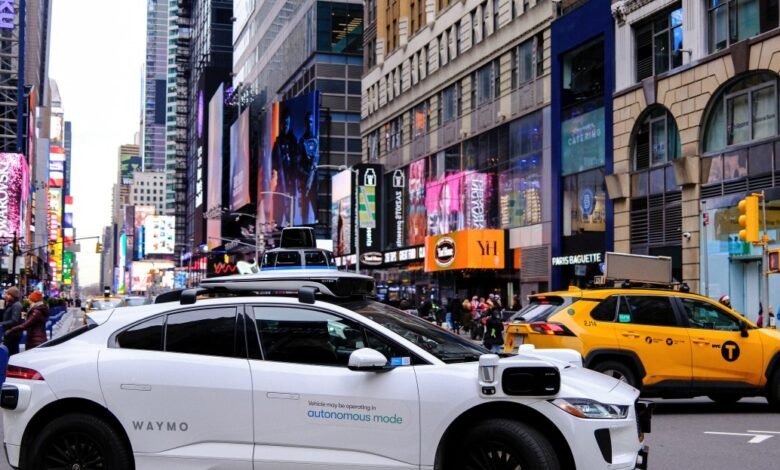 Waymo autonomous vehicle and yellow taxi in busy Times Square, NYC.