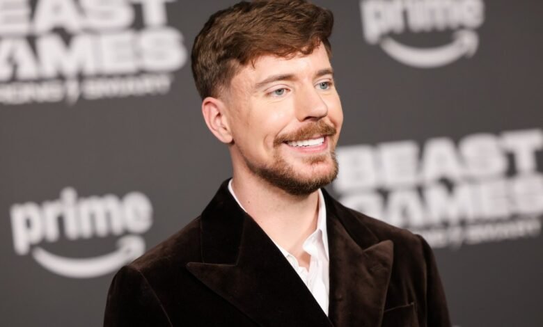 MrBeast at event with 'Beast Games' backdrop, smiling.