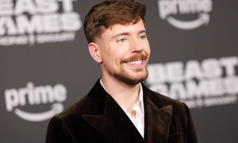 MrBeast at event with 'Beast Games' backdrop, smiling.