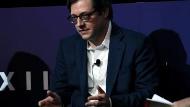 Nathaniel Rich speaks at event, wearing glasses and a suit.