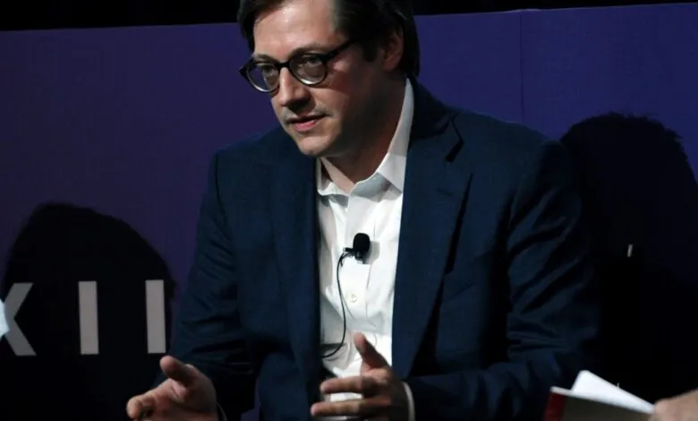 Nathaniel Rich speaks at event, wearing glasses and a suit.