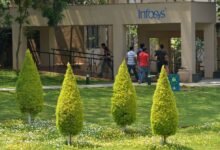 Infosys campus entrance with employees walking in Bangalore, India.