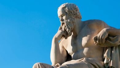 Statue of Socrates against a bright blue sky, deep in thought.
