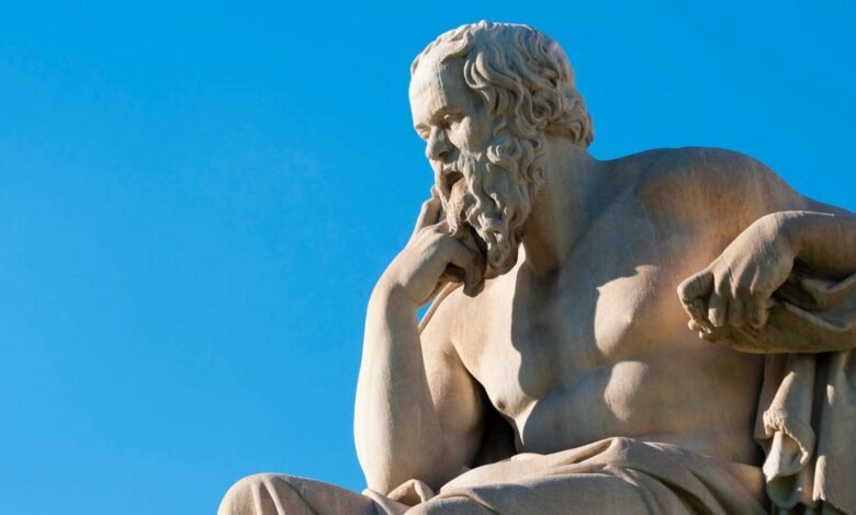Statue of Socrates against a bright blue sky, deep in thought.