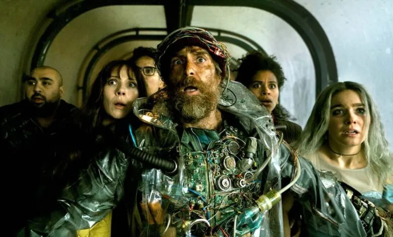 Group of people with shocked expressions, one wearing a circuit board vest.