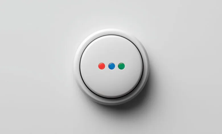 White circular button with red, blue, and green dots on a white surface.