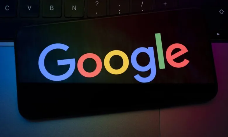 Google logo displayed on a smartphone screen atop a laptop.