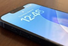 Close-up of an iPhone screen displaying the time and date on a blue background.