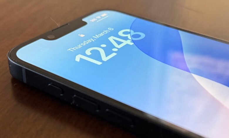 Close-up of an iPhone screen displaying the time and date on a blue background.