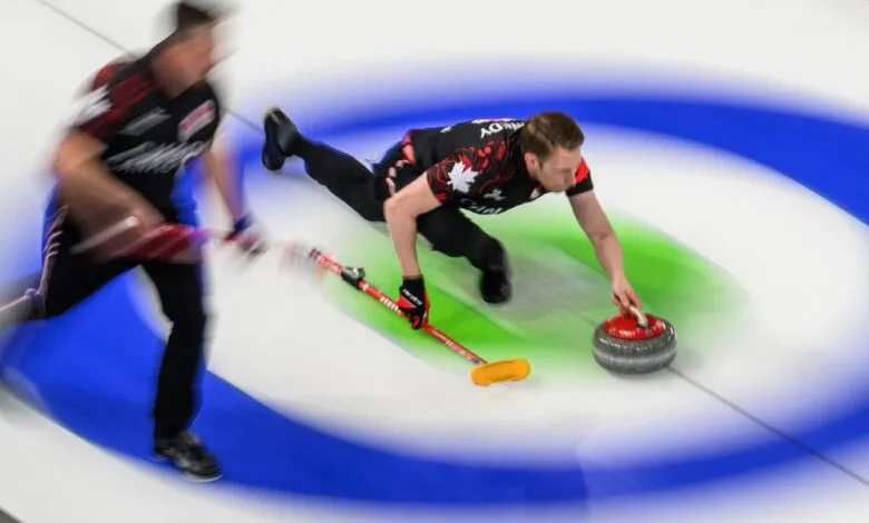 Curling athlete slides, releasing stone on ice rink.