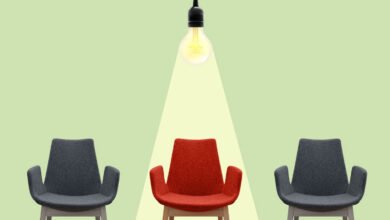 Three chairs, one red under a spotlight, two gray on either side.
