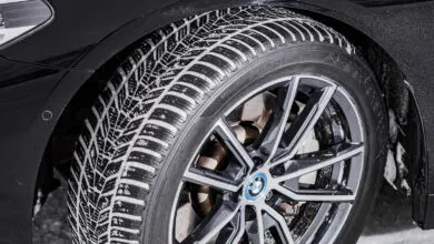 Close-up of a car tire with snow on the tread and a BMW logo on the wheel.