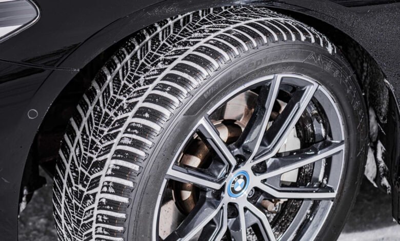 Close-up of a car tire with snow on the tread and a BMW logo on the wheel.
