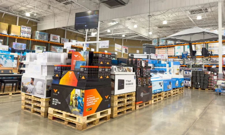 Electronics and outdoor gear displayed on pallets in a warehouse store.