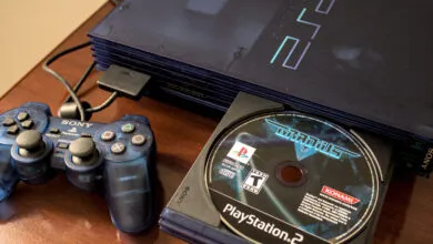 Blue PlayStation 2 console with controller and Gradius V game disc.
