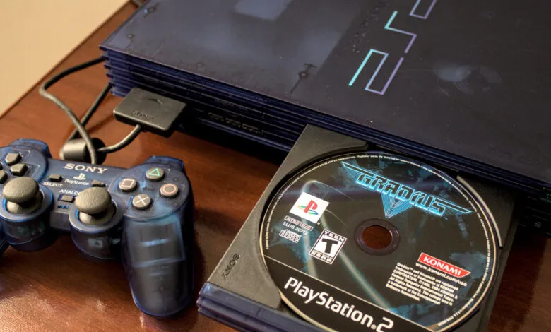 Blue PlayStation 2 console with controller and Gradius V game disc.