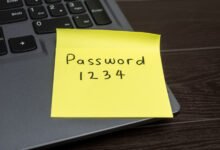 Yellow sticky note with 'Password 1234' on laptop keyboard.