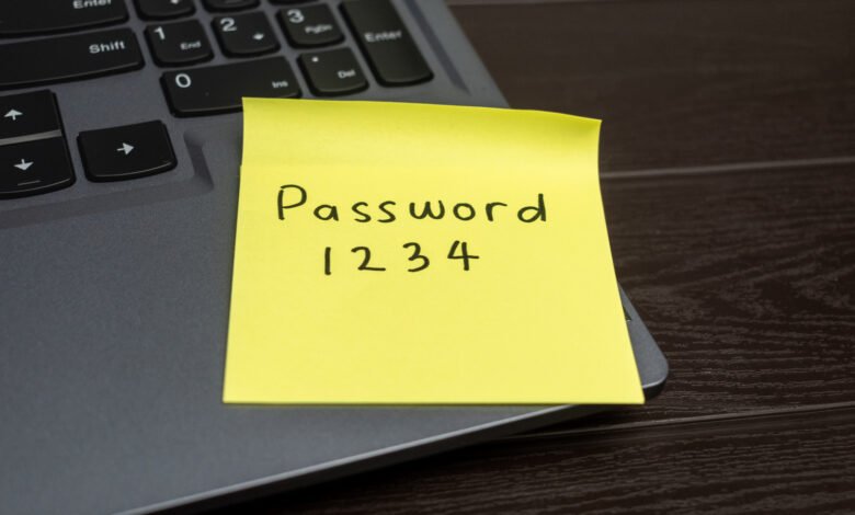 Yellow sticky note with 'Password 1234' on laptop keyboard.