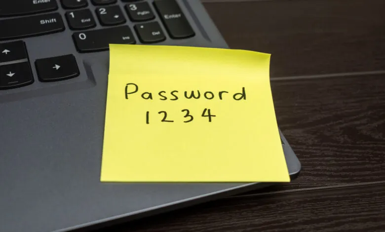 Yellow sticky note with 'Password 1234' on laptop keyboard.