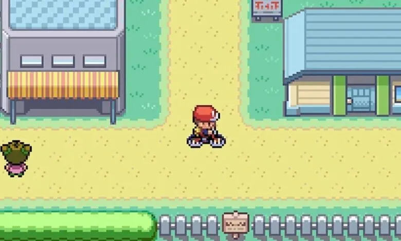 Pixelated game scene with character on bike, buildings, and grassy areas.