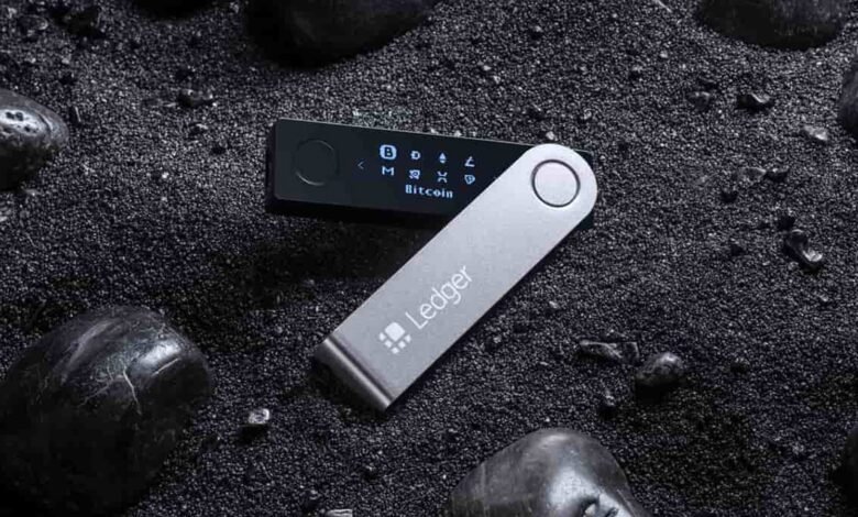 Ledger Nano X hardware wallet for cryptocurrency storage on black sand.