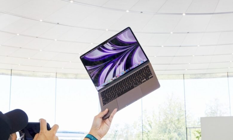 Person holds up purple M2 MacBook Air in bright, modern space.