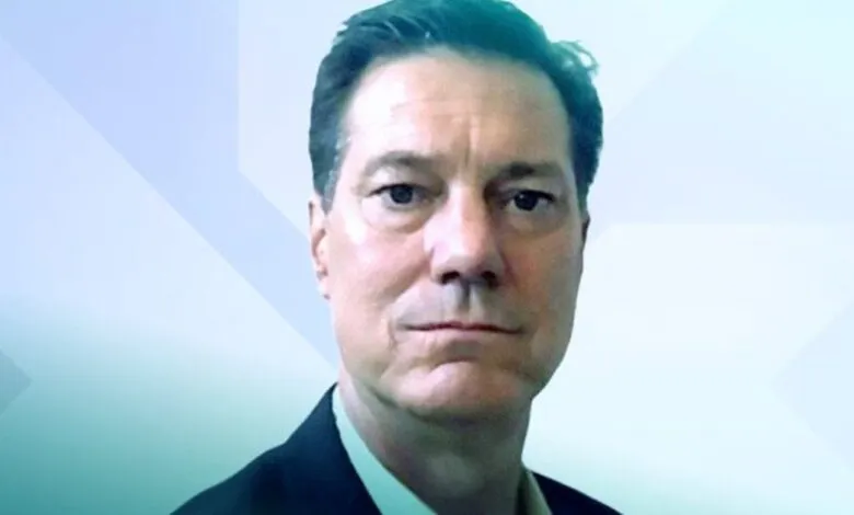 Headshot of Mike Wallen against a geometric background.