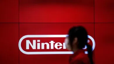 Large Nintendo logo on red wall with blurred person in foreground.