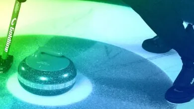 Curling stone and broom on ice with a person wearing curling shoes.