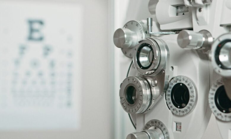 Close-up of a white phoropter with an eye chart in the background.