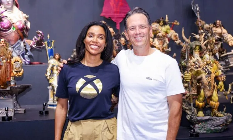 Sarah Bond and Phil Spencer pose in front of Warcraft statues.