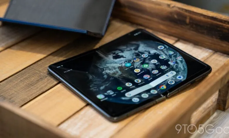 Foldable smartphone displaying home screen with Earth wallpaper on a wooden tray.