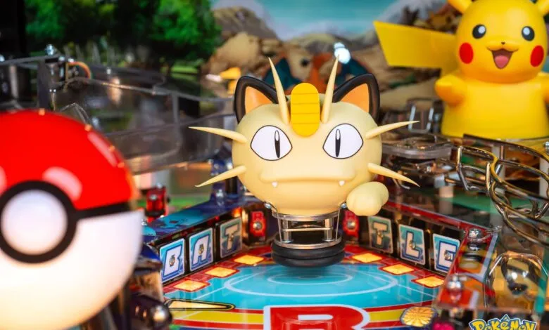 Close-up of a Pokémon pinball machine featuring Meowth and Pikachu figures.