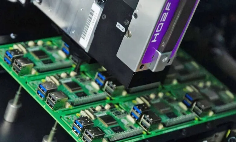 Automated machine placing components on a green circuit board.