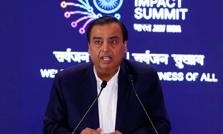 Mukesh Ambani speaking at Impact Summit, wearing a dark suit.