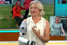Woman with robotic arm on TV show, smiling and gesturing.