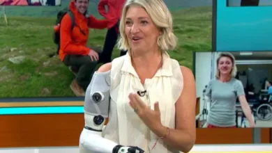 Woman with robotic arm on TV show, smiling and gesturing.