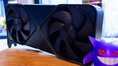 Black graphics card with two fans next to a purple Gengar figure.