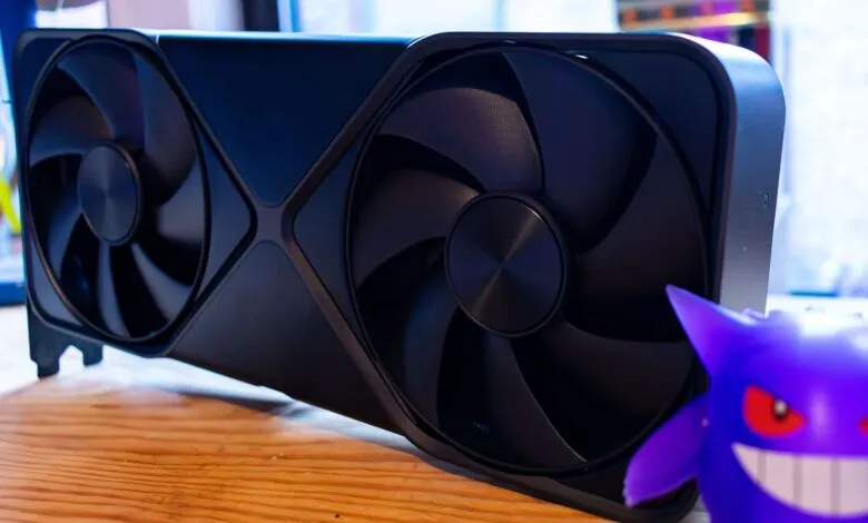 Black graphics card with two fans next to a purple Gengar figure.