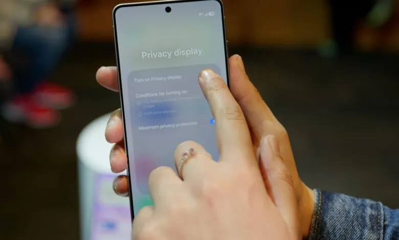 Close-up of a phone displaying 'Privacy display' settings being touched.