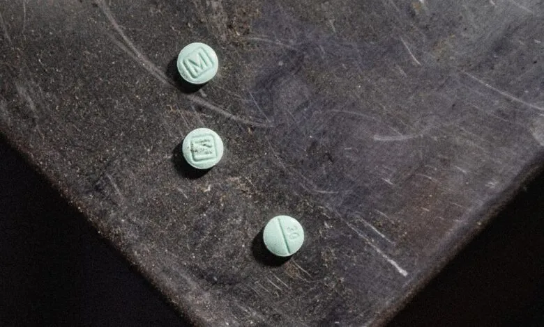 Three small, round, light green pills on a dark, scratched surface.