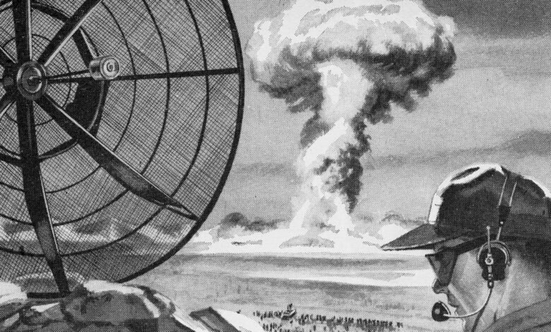 Black and white image of a man observing a nuclear explosion.