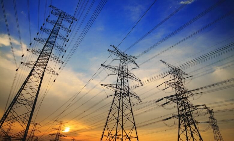 Several high-voltage power lines and towers against a colorful sunset sky.