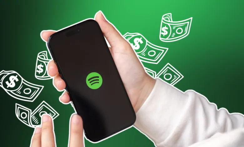 Hand holding phone with Spotify logo, money graphics around.