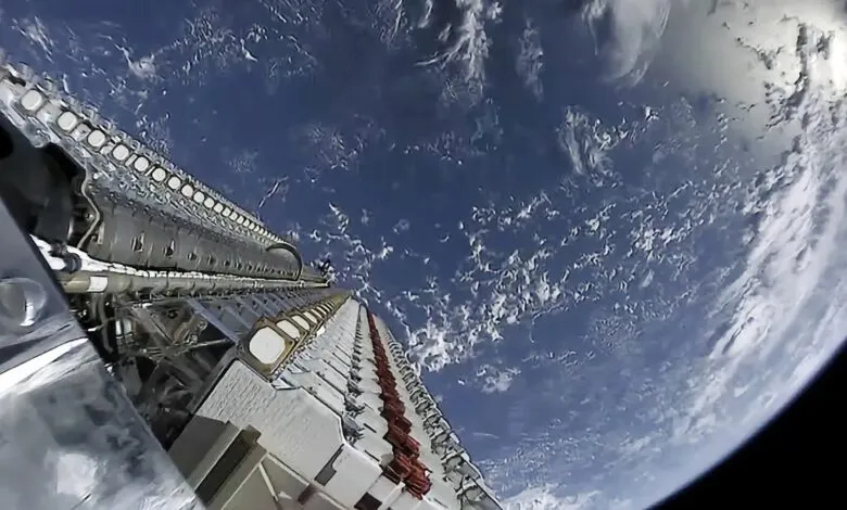 View of Starlink satellites in orbit above Earth, showing the planet's curvature and cloud cover.