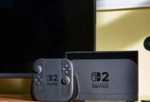 Nintendo Switch 2 console, controller, and camera on a wooden surface.