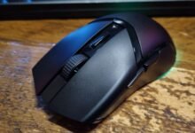 Close-up of a black wireless gaming mouse on a wood surface.