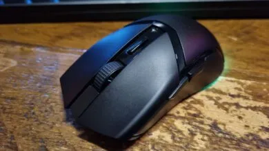 Close-up of a black wireless gaming mouse on a wood surface.